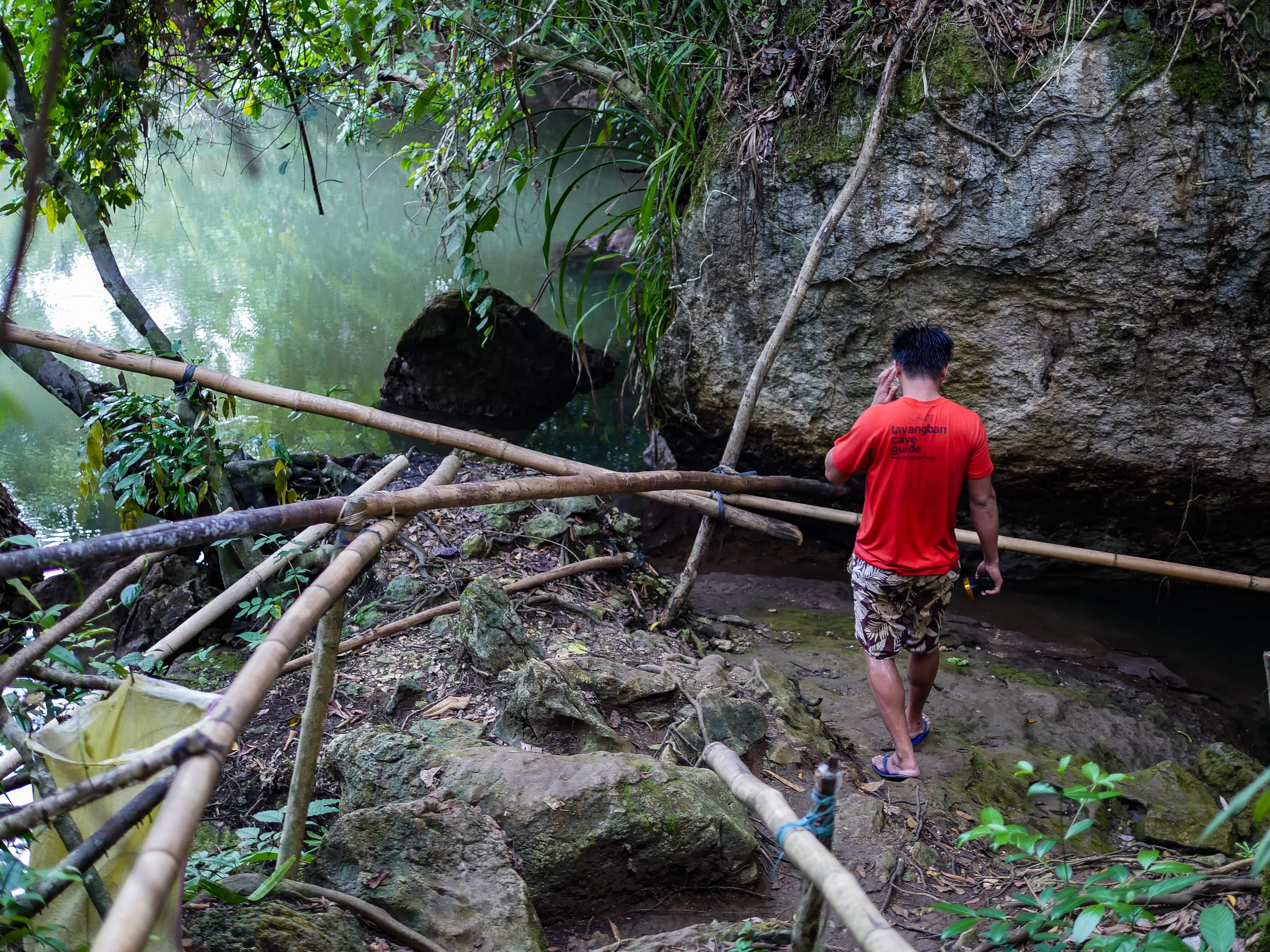 guide leading visitor towards entrance of tayangban cave in siargao philippines